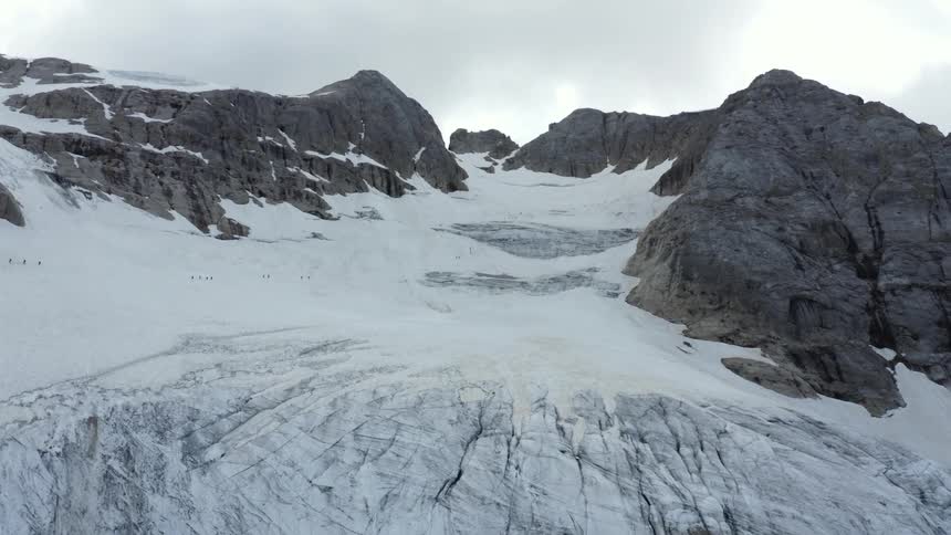 People walk across a glacier in a mountain valley