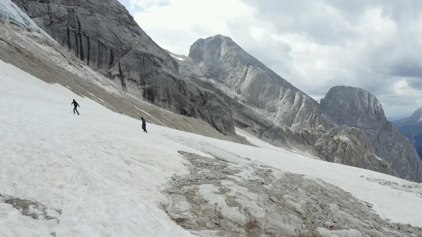 Two people hiking and climbing a snowy mountain