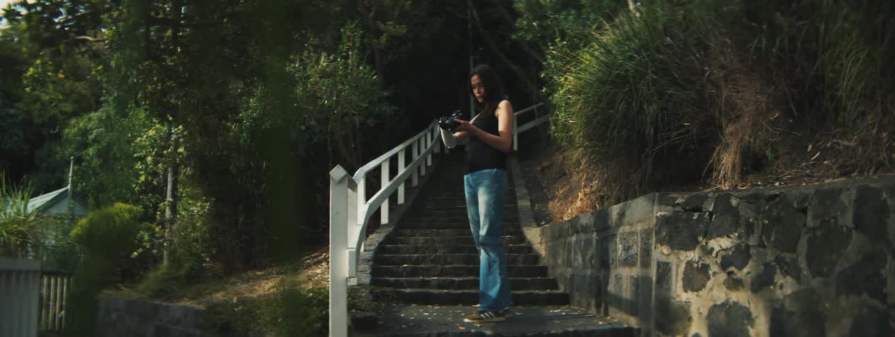 A woman walking down stone steps and holding a camera with her mechanical prosthetic arm