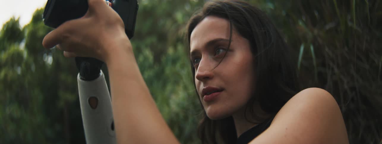 Photographer with an artificial arm aims her camera while standing outdoors