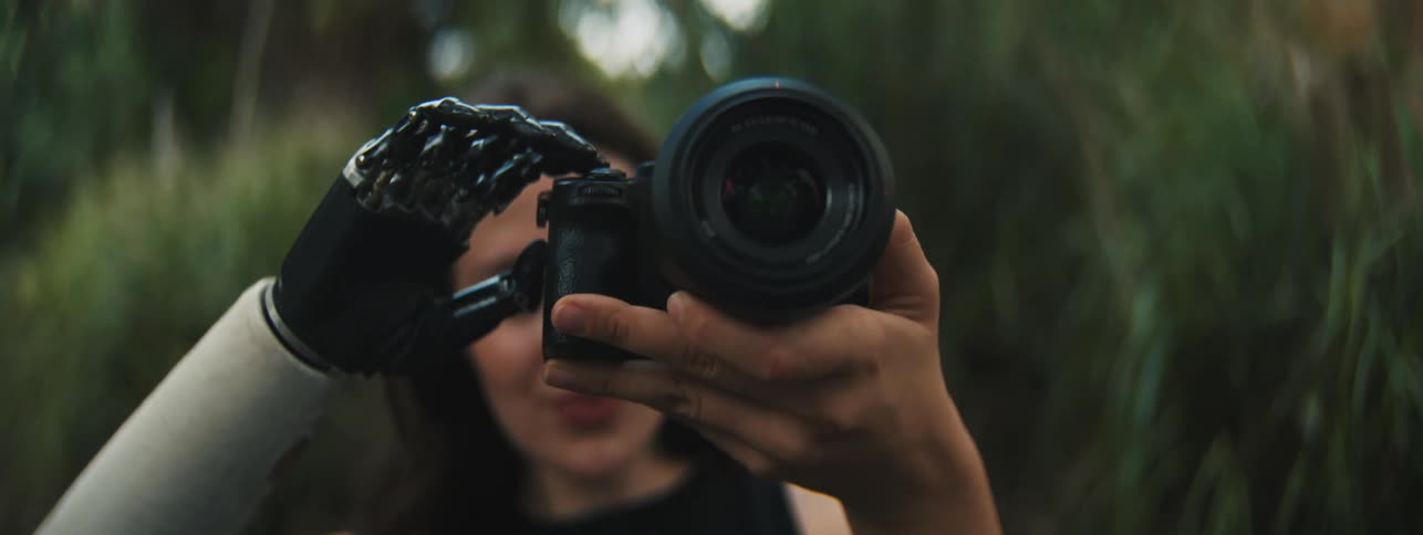 A woman holding a camera with her hand and she has a prosthetic arm