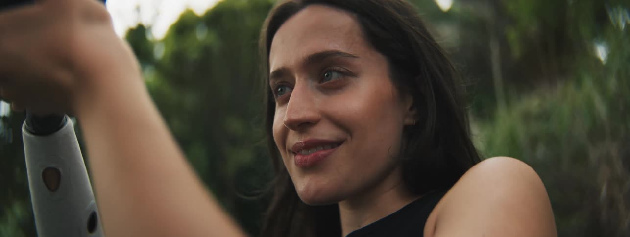 Portrait of a concentrated young woman giving a slight smile while standing outdoors in the flora