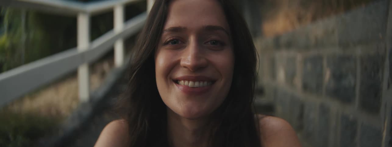 A woman sits outdoors smiling