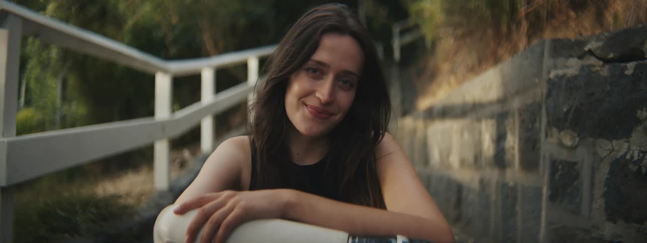 Young woman sitting on the steps of an outer neighborhood giving a slight smile