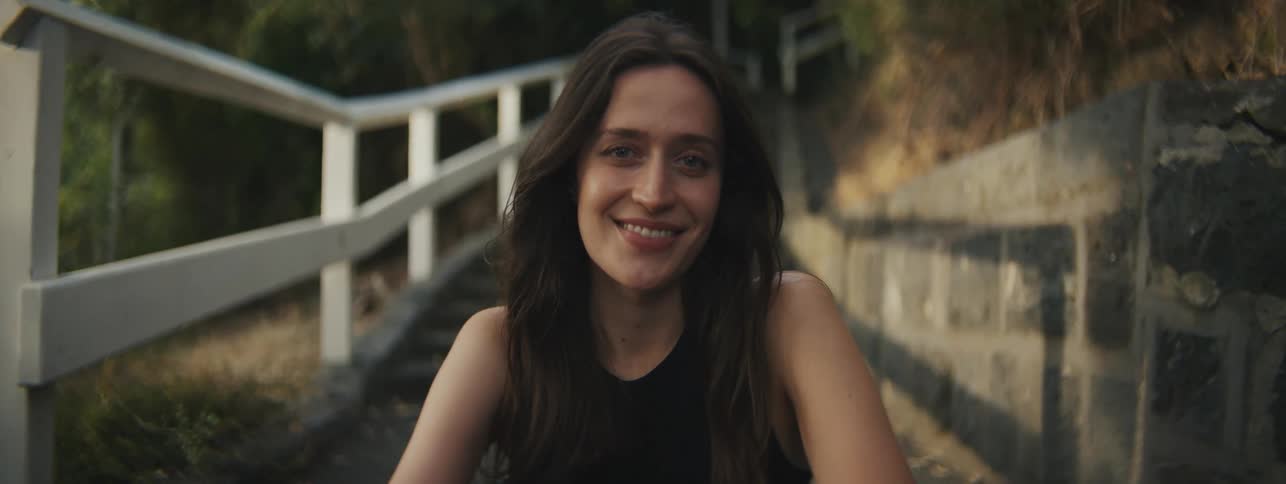 Young woman sitting on the steps of a neighborhood smiling