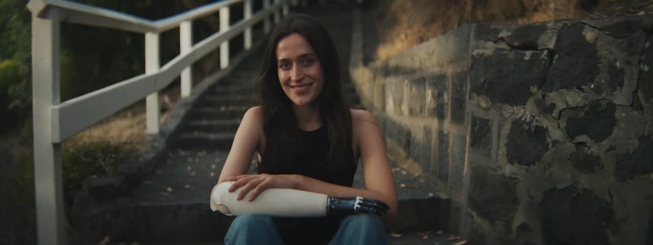 A woman with a prosthetic limb is smiling outside