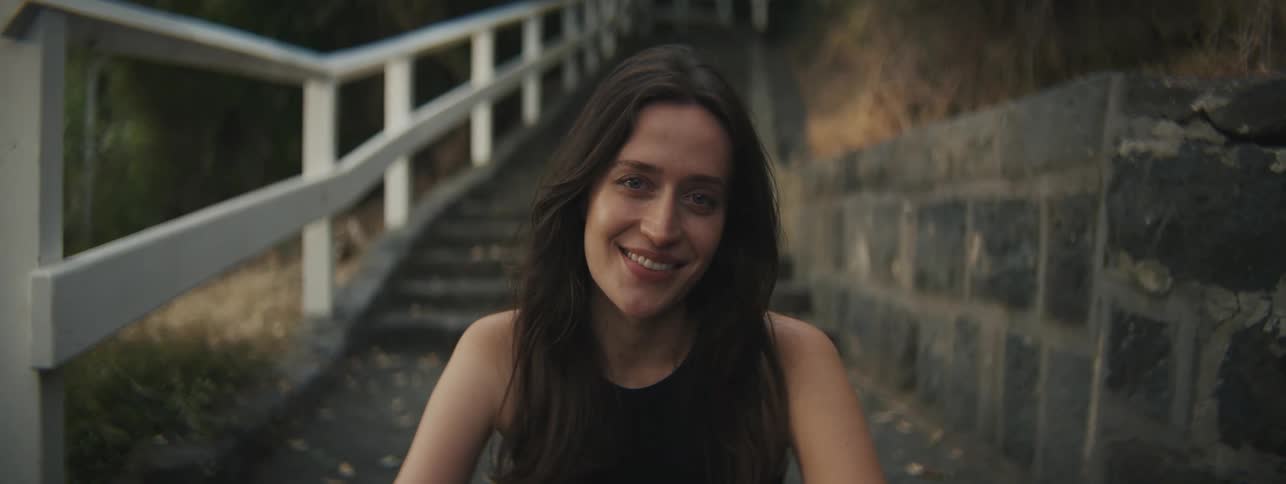 Portrait of a young woman with a smile while sitting by a staircase in a neighborhood