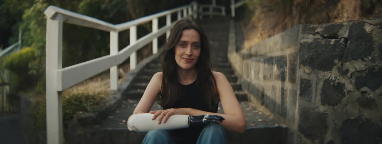 A woman with a prosthetic arm sits outside