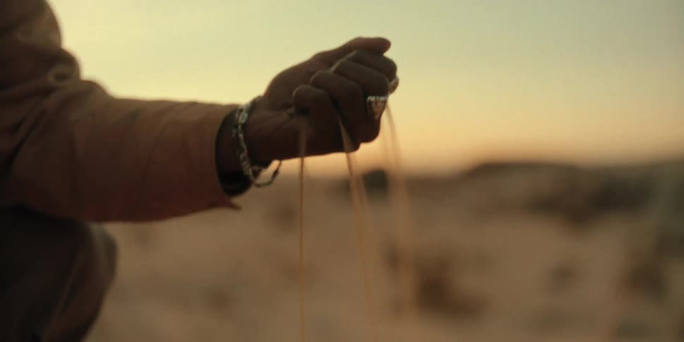Person is in the desert and pouring sand from their hand