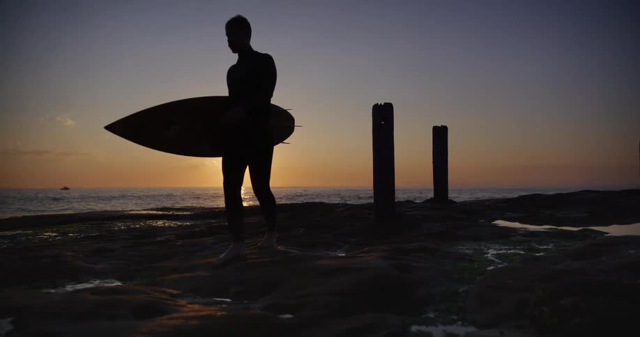 A surfer carries a board along a beach