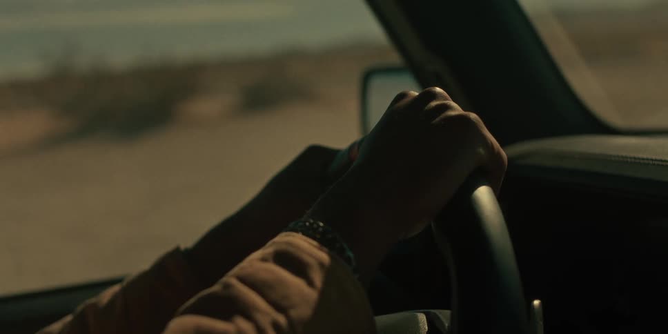 Male driver holds steering wheel in a vehicle in the desert on a cloudy day