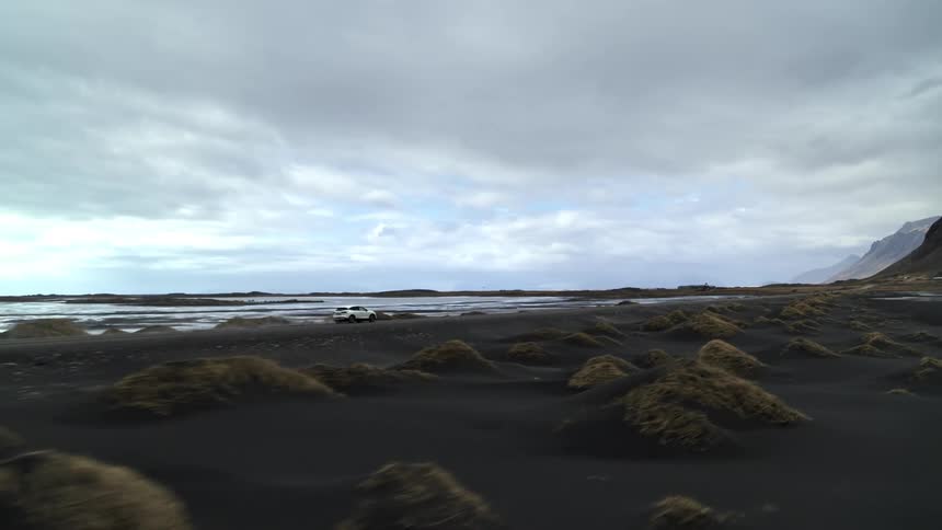 A vehicle drives past the shore