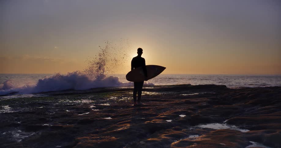 A surfer is watching the sunrise