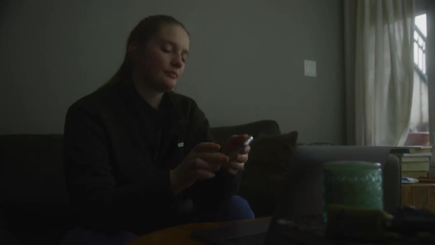 A woman picks up a smartphone in a living room