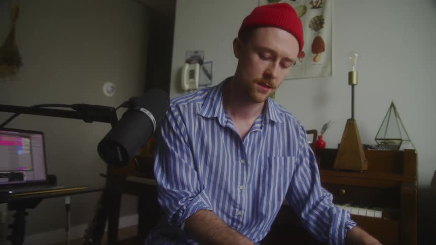 A young male musician plays the keyboard indoors
