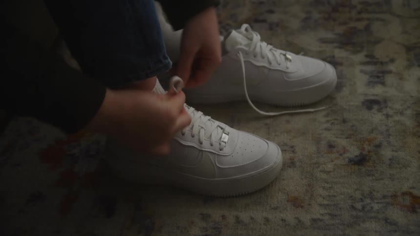 Womans hands tying laces on white sneakers