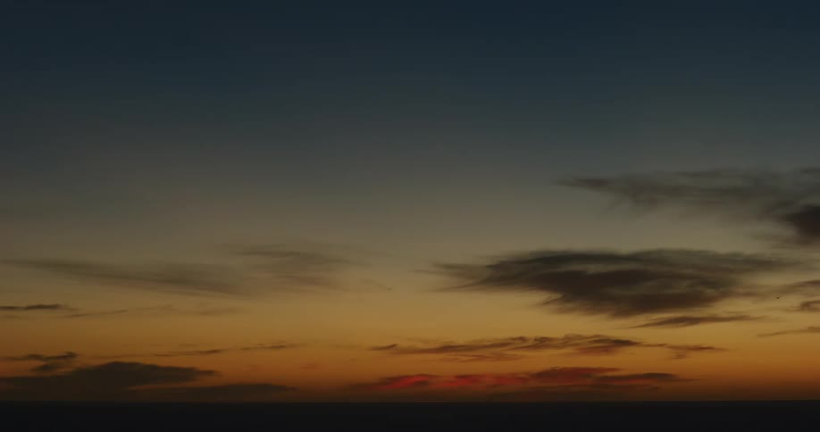 Wide shot of the sun setting in the cloudy horizon