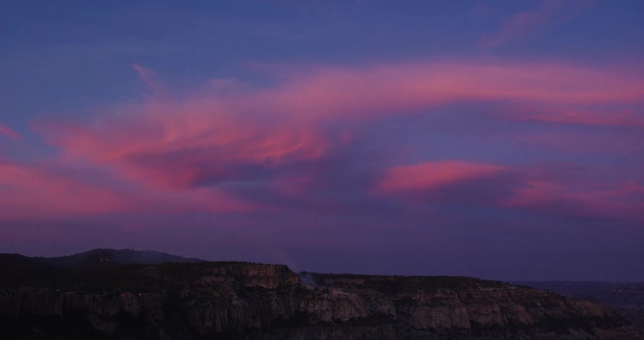 Sun is setting on a cloudy day over a rocky landscape