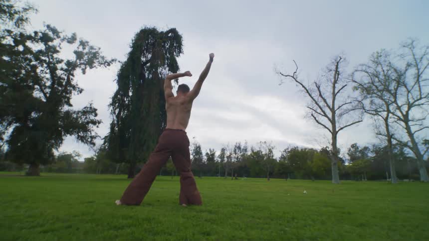 Man dancing alone in an empty grassland area