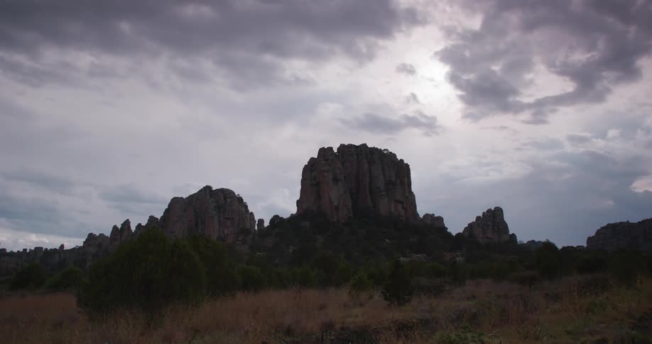 Sun shines through clouds onto mesa and the surrounding grassland