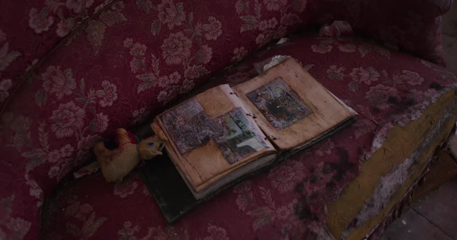A red wornout couch with an old photo album lying open on top of it