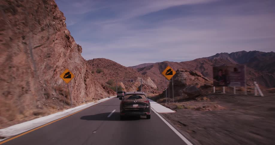 Vehicles drive down a road surrounded by mountains