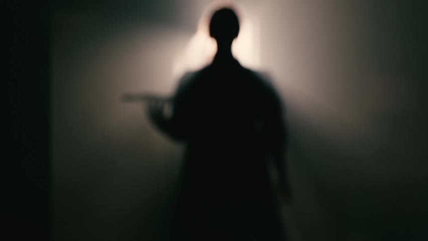 A woman walks through the dark hall with a tray of food