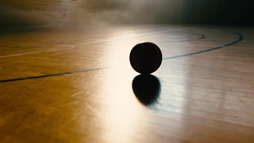 Basketball ball rolling on a closed wooden court