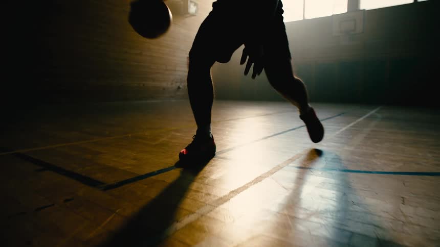A man dribbles a basketball on a court