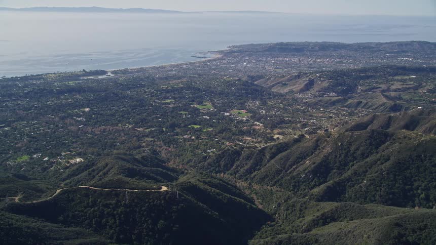 Aerial view of a coastal city between green mountains and the ocean