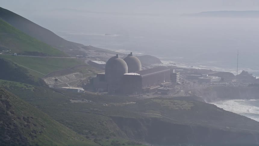 Aerial panorama of a factory by the sea and next to a mountain