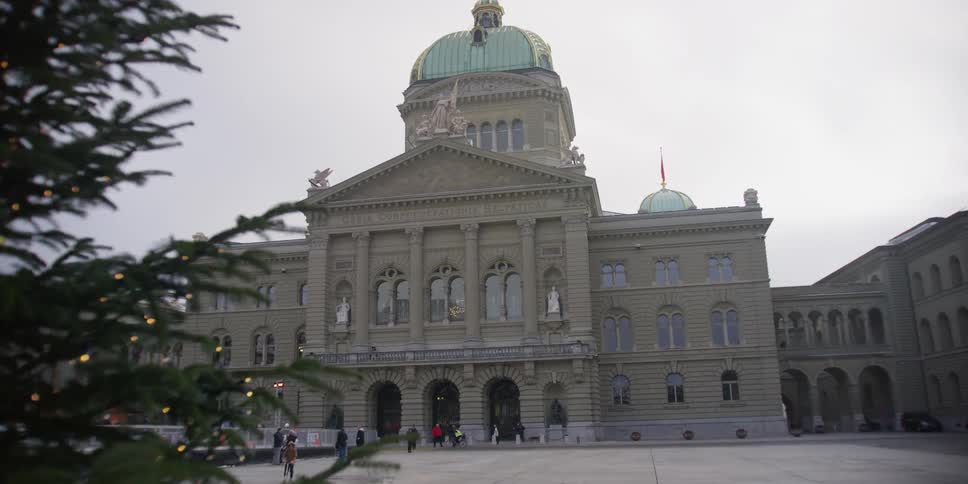 Historic Swiss Parliament building on Bundesplatz Square in Bern, Switzerland with visiting pedestrians and vehicles passing by.