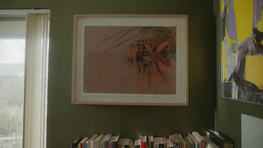 A framed piece of artwork hangs on a wall in a house