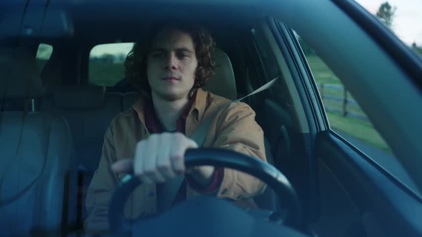 Outside windshield view of a man driving a car