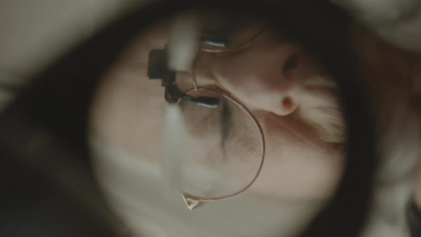 Point of view through a magnifying glass of a concentrated lady working