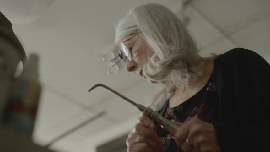 An old woman works with sculpting tools