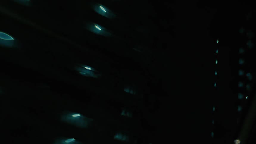 Point of view from the sunroof of a vehicle moving through the city at night with buildings and skyscrapers