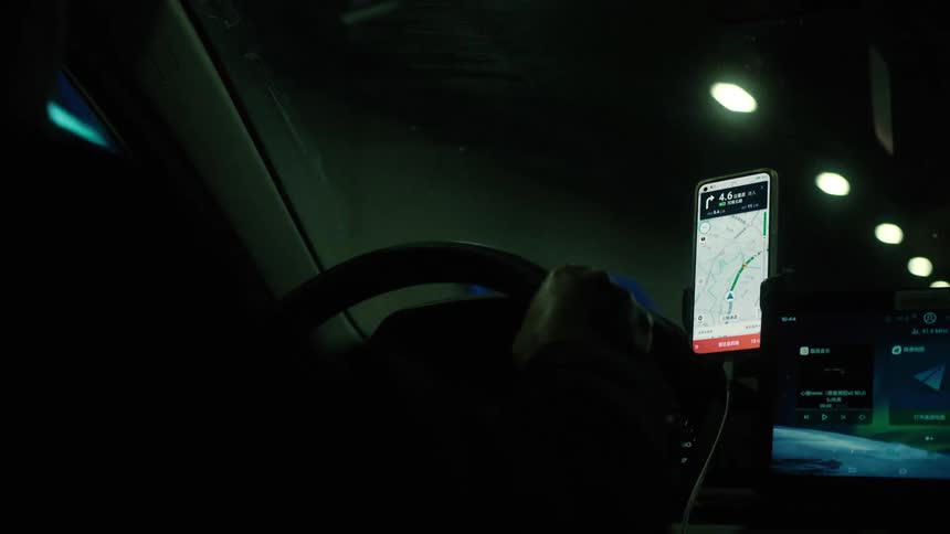 Hands of a man driving a vehicle with his smartphone with gps next to the steering wheel while traveling in a tunnel through the city