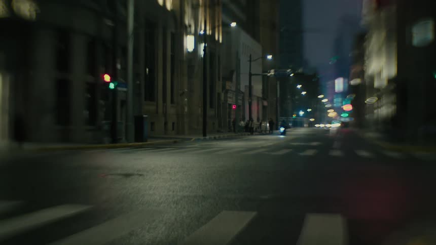 Motorcyclist approaches downtown intersection at night