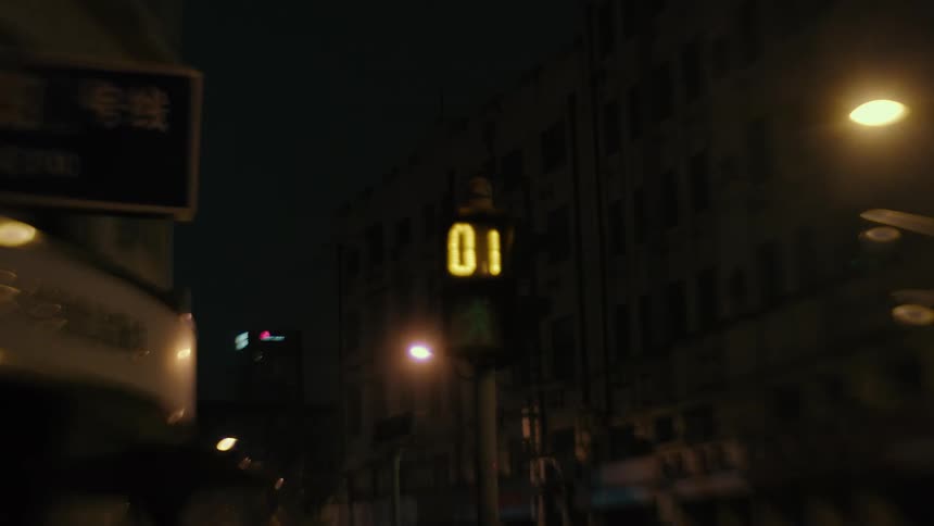 Pedestrian walks through city intersection at night