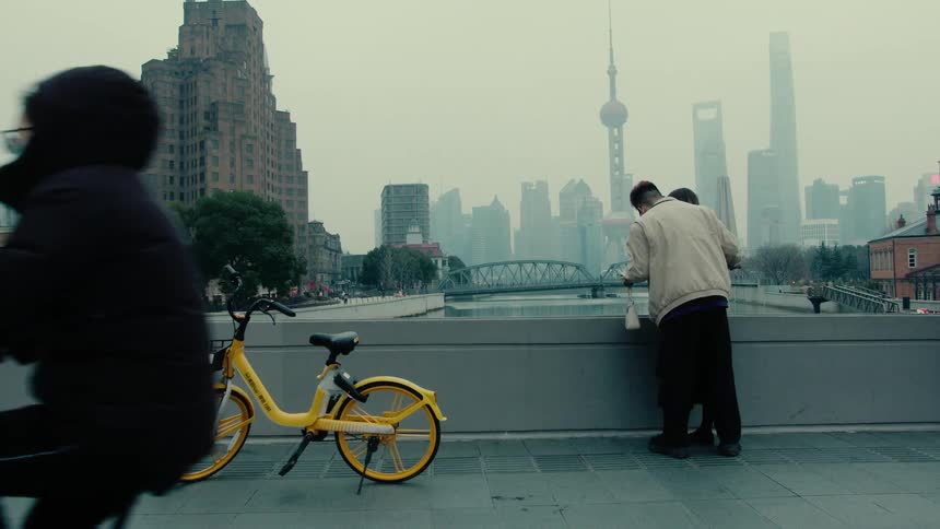 Couple on a bridge over a river overlooking the skyscrapers of the shanghai metropolis