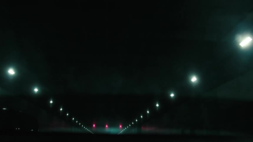 View of the rear windshield of a vehicle passing over an overpass at night