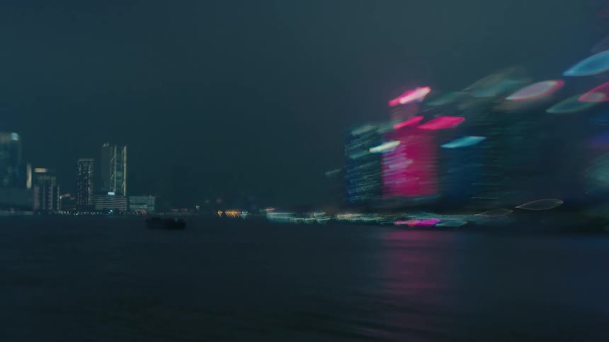 Blurred panorama of a metropolis with a skyscraper by the sea at night