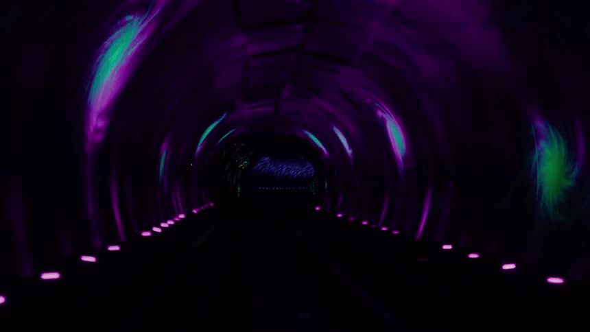 The tunnel is dark with neon lights on the walls