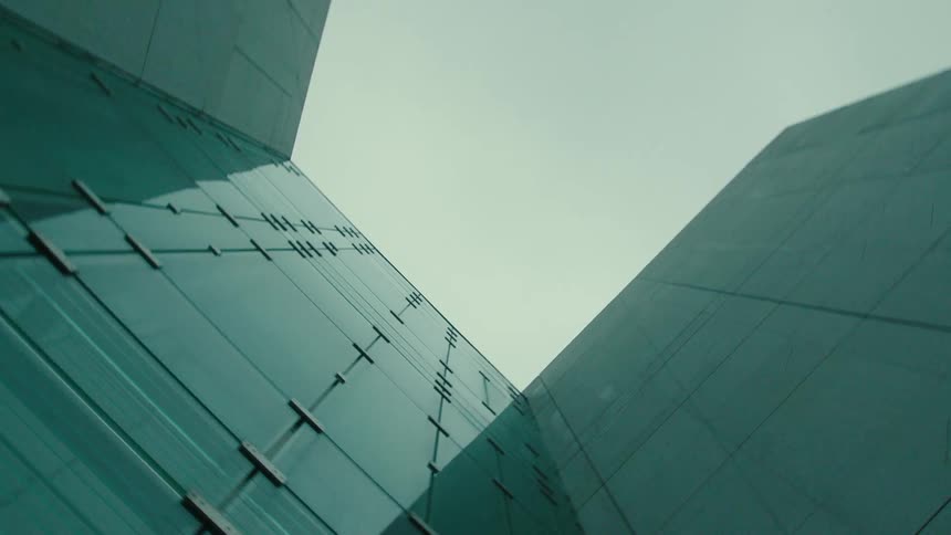 Upward view of a mirrored glass building on a cloudy day