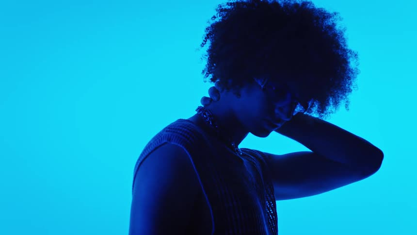 Model man posing with one hand on the back of his head in a studio with neon lights