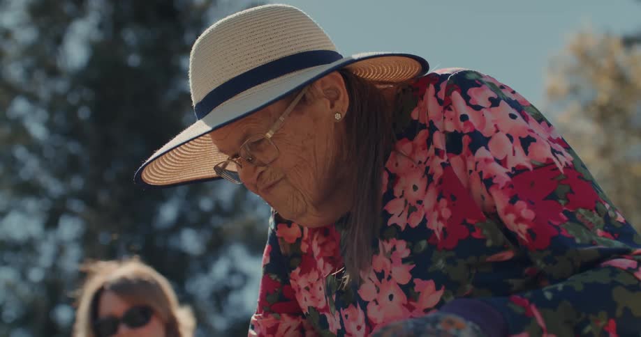 Portrait of an elderly woman wearing a hat next to a woman standing outdoors