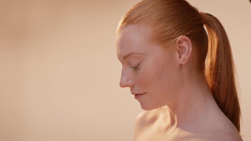 Close up of a beautiful model applying cream to her face
