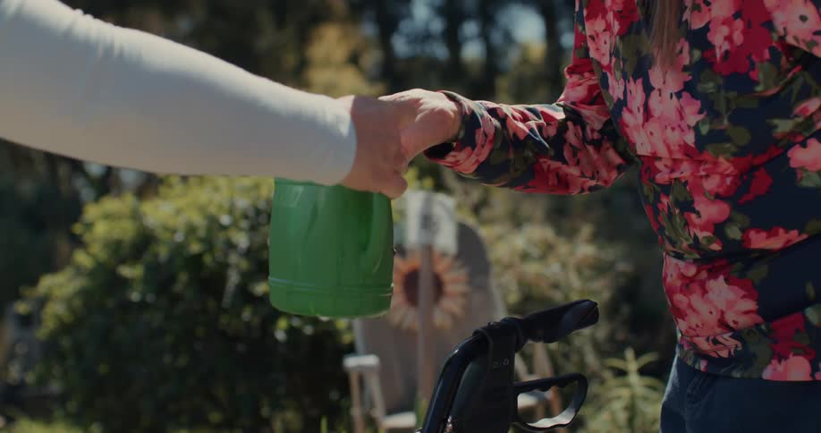 Hands of one person handing another a jug of gardening water