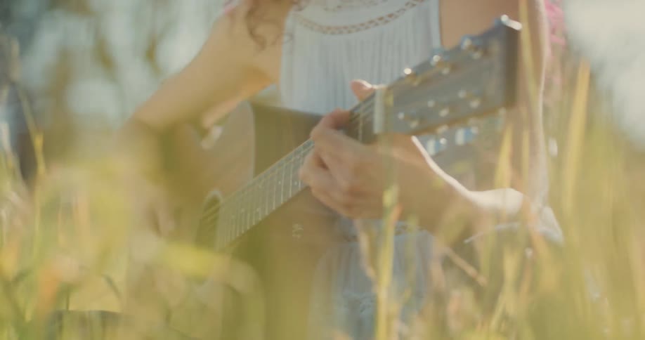 A woman is playing the guitar in the grass